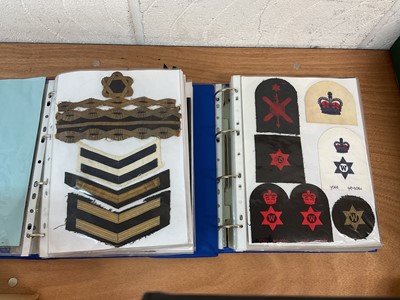 Lot 759 - Two albums of cloth Royal Navy badges and insignia to include cap tallies (2 albums)