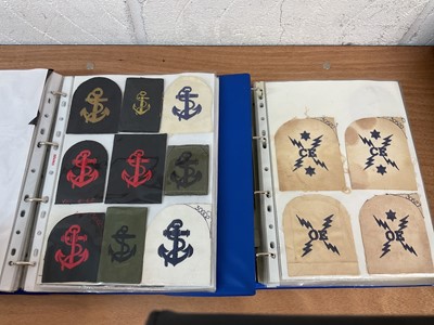 Lot 759 - Two albums of cloth Royal Navy badges and insignia to include cap tallies (2 albums)