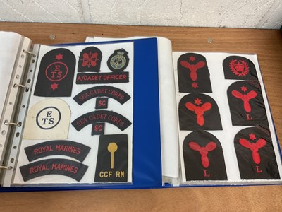 Lot 759 - Two albums of cloth Royal Navy badges and insignia to include cap tallies (2 albums)