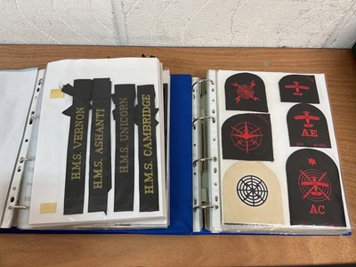 Lot 759 - Two albums of cloth Royal Navy badges and insignia to include cap tallies (2 albums)