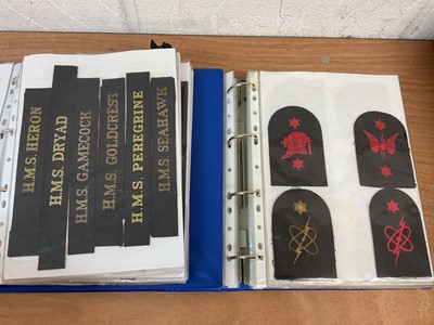 Lot 759 - Two albums of cloth Royal Navy badges and insignia to include cap tallies (2 albums)