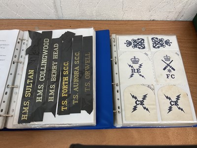 Lot 759 - Two albums of cloth Royal Navy badges and insignia to include cap tallies (2 albums)