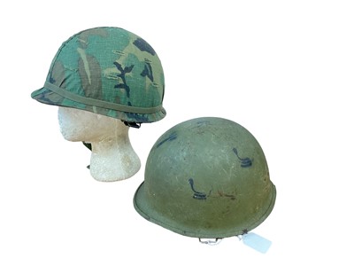 Lot 783 - American M1 steel helmet complete with liner, chinstrap and camouflage cover, together with another American M1 steel helmet (2)