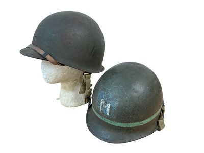 Lot 787 - American M1 steel helmet complete with liner, chinstrap and cover, together with another American M1 steel helmet (2)