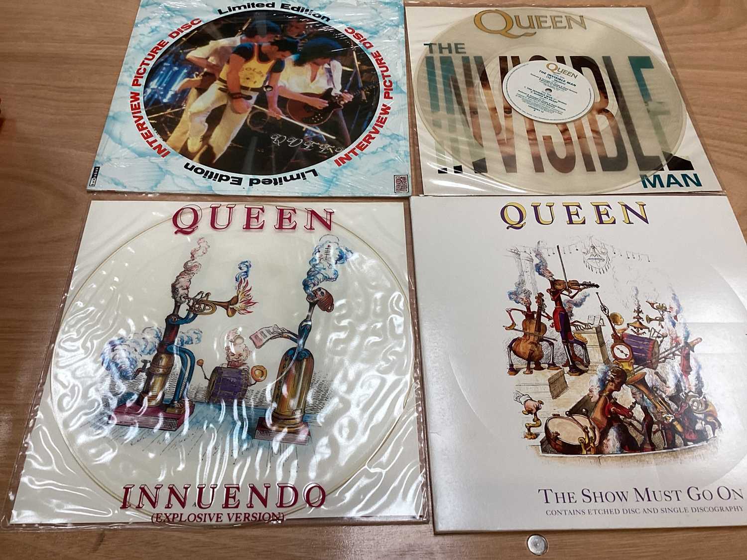 Lot 2217 - Box of Queen related items including 7 inch singles (Queen DJ 95 - purple vinyl limited edition, etc), 12 inch singles and books (40 Years of Queen and The Neal Preston Photographs, etc), together...