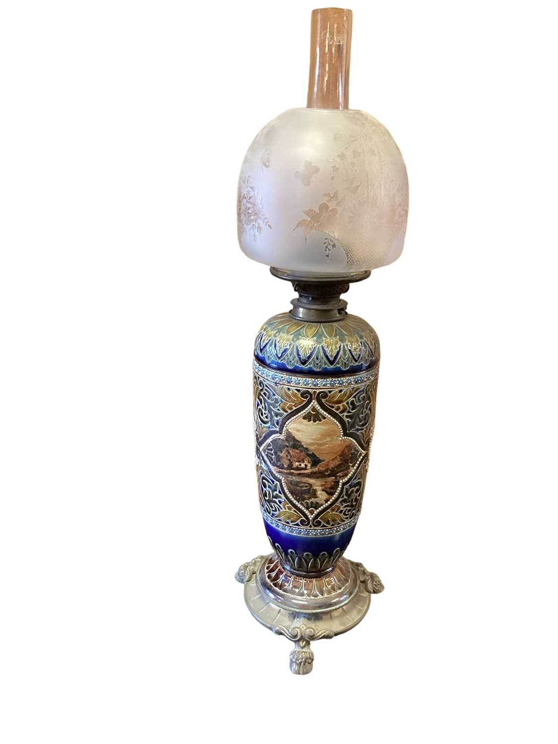 Lot 1254 - Doulton Lambeth oil lamp with glass shade and chimney, raised on brass feet