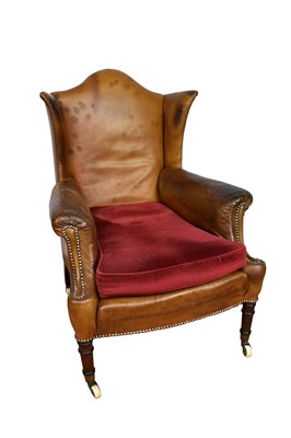 Lot 1061 - Early 19th century leather upholstered wing armchair, raised on ring turned legs and castors