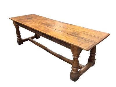 Lot 1074 - 17th century style oak refectory table, the plank top with cleated ends, with boss carved frieze on bulbous baluster supports and H-shaped stretcher, 243 x 77cm