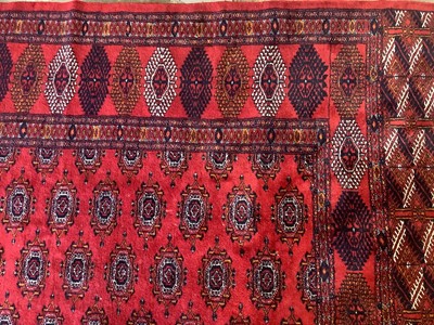 Lot 1252 - Large Bokhara carpet with thirteen rows of twenty-nine medallions on blood red ground with multiple geometric borders, 310cm x 440cm