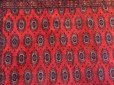 Lot 1252 - Large Bokhara carpet with thirteen rows of twenty-nine medallions on blood red ground with multiple geometric borders, 310cm x 440cm