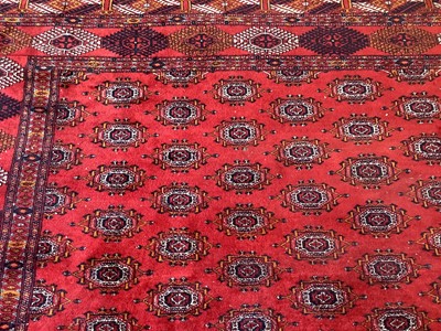 Lot 1252 - Large Bokhara carpet with thirteen rows of twenty-nine medallions on blood red ground with multiple geometric borders, 310cm x 440cm