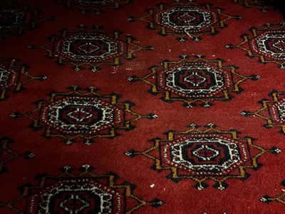 Lot 1252 - Large Bokhara carpet with thirteen rows of twenty-nine medallions on blood red ground with multiple geometric borders, 310cm x 440cm