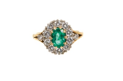 Lot 439 - Emerald and diamond cluster ring with an oval mixed cut emerald measuring approximately 7.4 x 4.9mm, surrounded by a border of ten round brilliant cut diamonds in claw setting with two further diam...