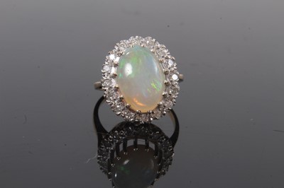 Lot 516 - Opal and diamond cluster ring with an oval opal cabochon measuring approximately 13 x 10mm surrounded by a border of brilliant cut diamonds in 9ct gold setting, ring size P.