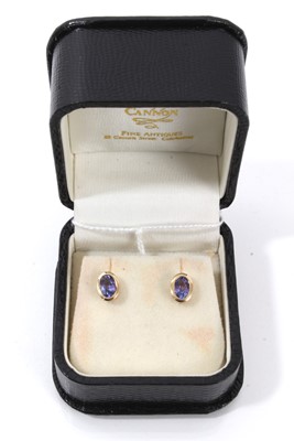 Lot 824 - Pair of tanzanite single stone earrings with an oval mixed cut tanzanite in 14ct yellow gold rub-over setting