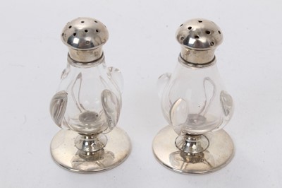 Lot 483 - Pair of Edwardian Art Nouveau silver and glass pepperettes, (Birmingham 1906), each 6.5cm in height.