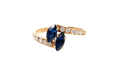 Lot 739 - Cartier sapphire and diamond cross-over ring with two marquise cut blue sapphires in a cross-over design with graduated brilliant cut diamonds to the shoulders on 18ct yellow gold shank, signed Car...