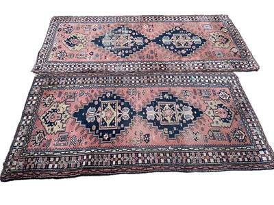 Lot 1713 - Near pair of Eastern rugs, each with conjoined medallions on salmon ground in geometric borders, the largest 210 x 105cm. (2)