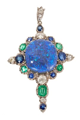 Lot 672 - A fine black opal diamond emerald and sapphire pendant, the cruciform pendant with a large oval black opal cabochon measuring approximately 20.50mm x 19.15mm x 6.30mm deep, surrounded by a border o...