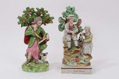 Lot 219 - Two early 19th century Staffordshire pearlware figures, including one showing a couple seated on a grassy mound with a dog, on a square lined based titled 'Rural Pastime', 22cm high, the other a fi...