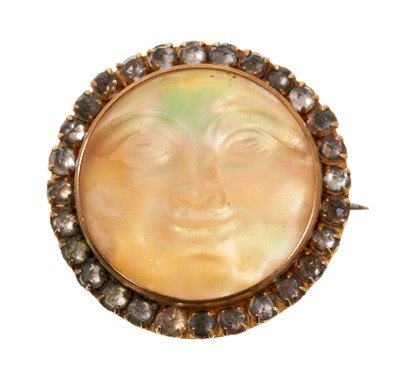 Lot 683 - Antique carved mother of pearl brooch in the form of the man on the moon, surrounded by a border of paste stones in gilt metal/yellow metal setting, 25mm diameter.