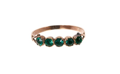 Lot 665 - Georgian gold and green paste ring with a band of five green paste stone in gold closed back setting on bifurcated shoulders a tapered shank, ring size N.