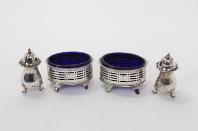 Lot 556 - Pair Victorian silver salts of oval form, with pierced decoration and blue glass liners, on pad feet (Sheffield 1890) James Deakin & Son, together with a pair of Edwardian silver baluster peppers (...