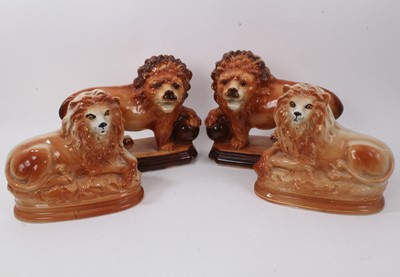 Lot 323 - Two large pairs of Victorian Staffordshire pottery lions, including one pair standing, each resting a paw on a ball, 28cm high, and a smaller recumbent pair, 25cm high