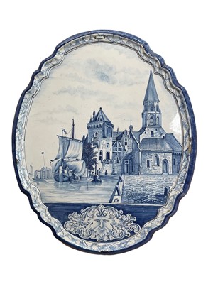 Lot 334 - A large Dutch delftware plaque, of shaped oval form, painted with a harbour scene, stylised mask and foliage at the bottom, 60cm x 49cm