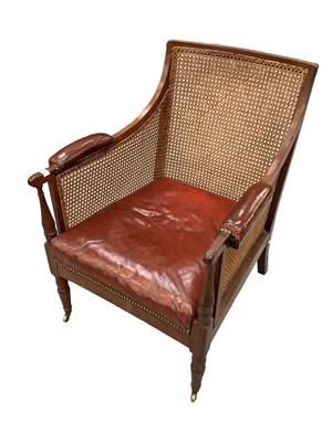 Lot 1669 - George IV mahogany bergère library chair, with drop in leather pad seat and arms on ring turned legs and castors