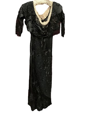 Lot 2104 - Edwardian evening dress in black satin with beaded net overlay, high waist and asymmetric draping and fringing.