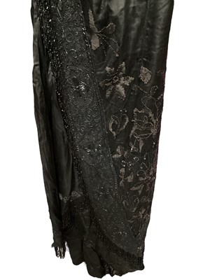 Lot 2104 - Edwardian evening dress in black satin with beaded net overlay, high waist and asymmetric draping and fringing.