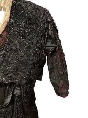 Lot 2104 - Edwardian evening dress in black satin with beaded net overlay, high waist and asymmetric draping and fringing.