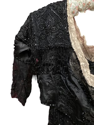 Lot 2104 - Edwardian evening dress in black satin with beaded net overlay, high waist and asymmetric draping and fringing.