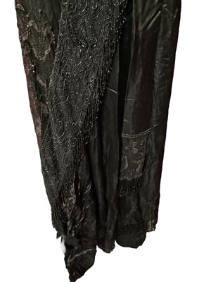 Lot 2104 - Edwardian evening dress in black satin with beaded net overlay, high waist and asymmetric draping and fringing.