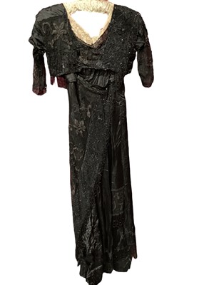Lot 2104 - Edwardian evening dress in black satin with beaded net overlay, high waist and asymmetric draping and fringing.