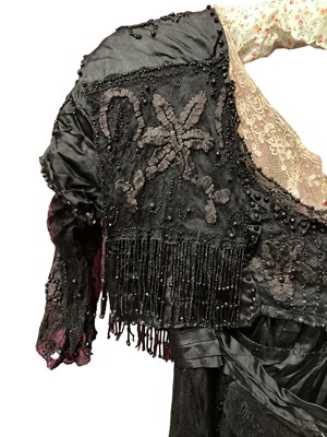 Lot 2104 - Edwardian evening dress in black satin with beaded net overlay, high waist and asymmetric draping and fringing.