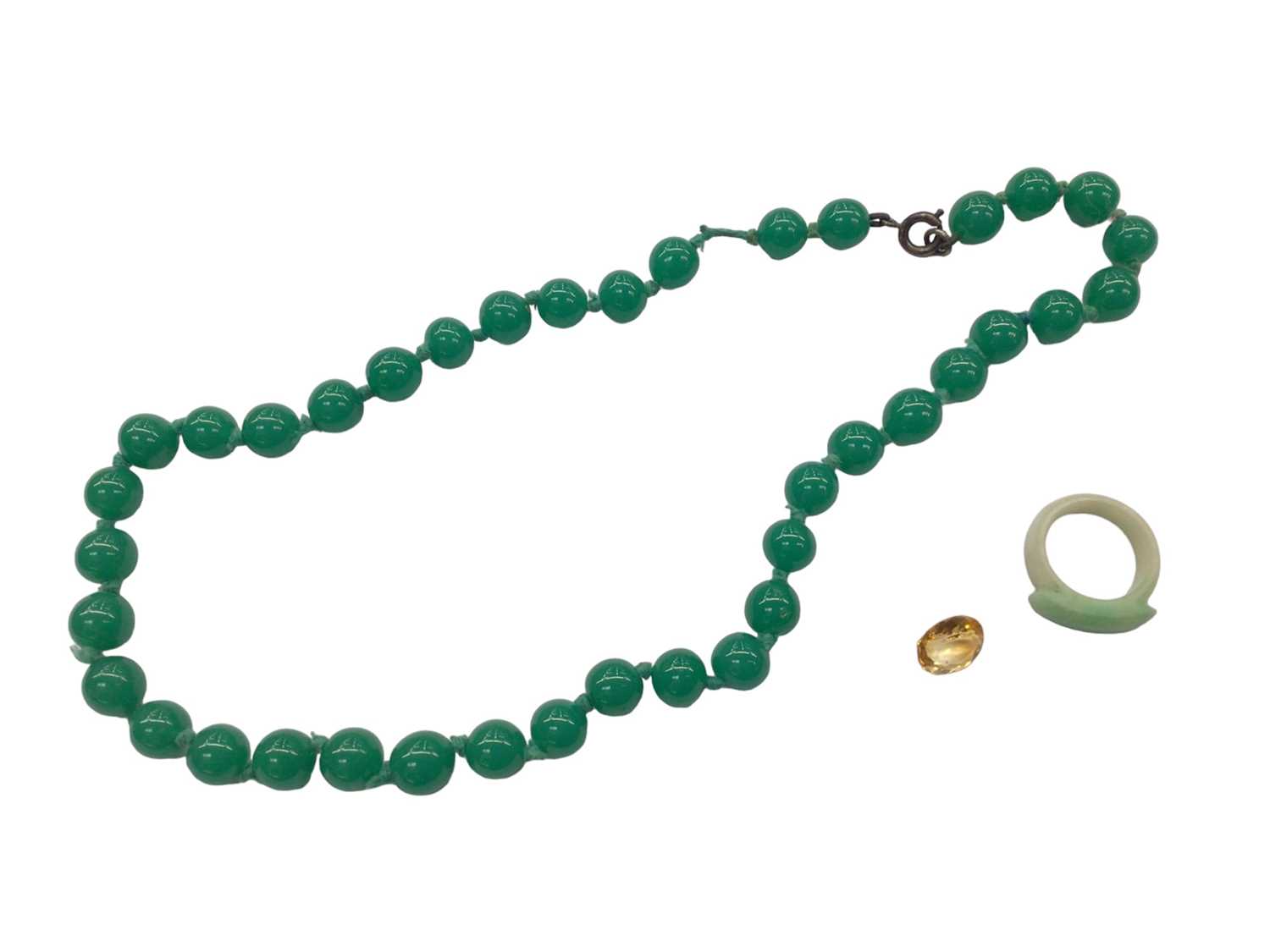 Lot 1018 - Green jade ring, green hard stone bead necklace, 48cm long and an unmounted oval mixed cut citrine