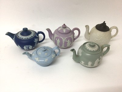 Lot 17 - A group of five 19th century English teapots, including one dark blue Wedgwood jasperware, one lilac jasperware, and three other relief-moulded examples
