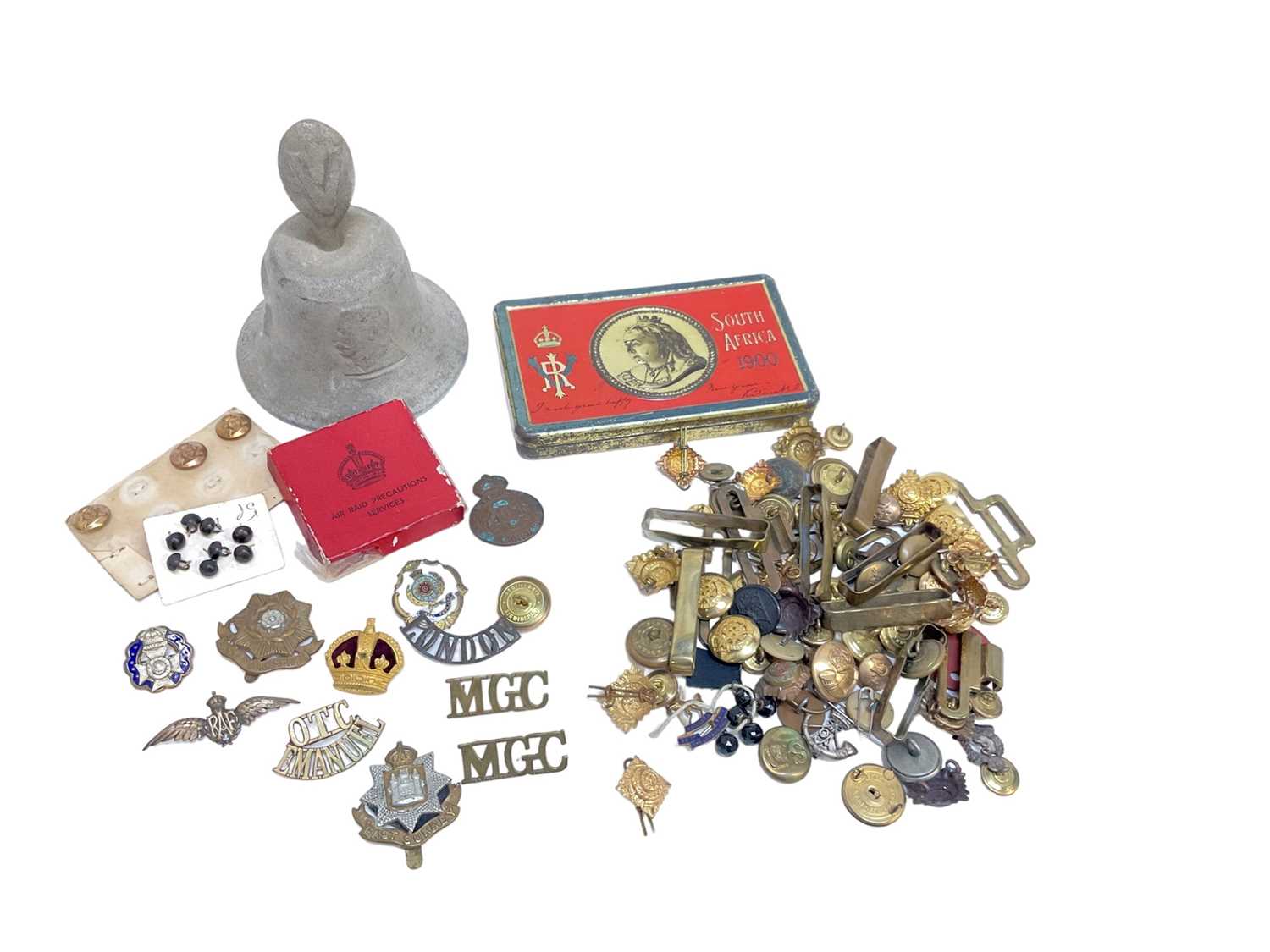 Lot 710 - Boer War Chocolate tin, together with a Second World War bell made from metal of shot down German aircraft and a group of cap badges and buttons (1 box).