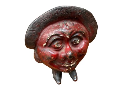 Lot 2563 - 1930s cast iron “Save and Smile” money box in the form of a smiling head mounted on two little feet, marked Made in England. 10.5cm overall height.