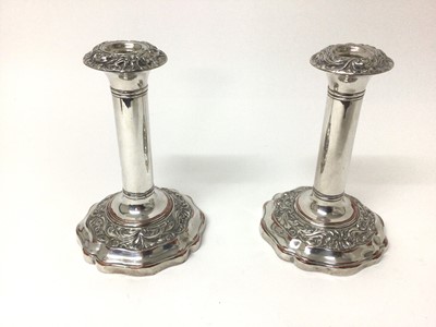 Lot 591 - Pair of Victorian silver plated candlesticks with foliate scroll decorated borders and shaped bases, 19cm high
