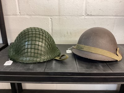 Lot 828 - 1950’s British military MK III steel helmet with green camouflage finish and net, with liner and chin strap, together with another similar MK III steel helmet (2)