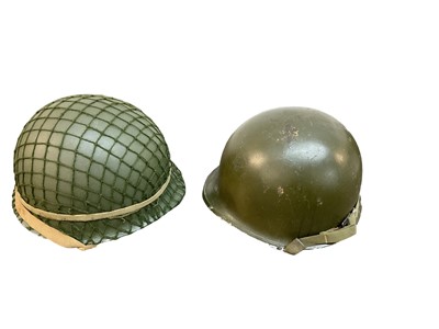 Lot 832 - American M1 steel helmet complete with liner, chinstrap and netting cover, together with another American M1 steel helmet (2)