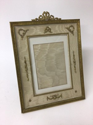 Lot 141 - Good quality Edwardian gilt metal photograph frame of retangular form with ribbon cresting and classical motif decoration on cream silk ground  with easel back 36 x 26 cm