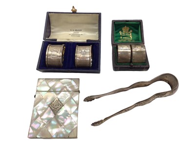 Lot 1016 - Pair of Victorian silver napkin rings with engraved swan crest, another pair of silver napkin rings, both in fitted cases, pair of plated sugar tongs and a mother of pearl card case with silver car...