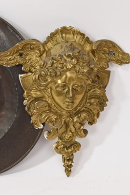 Lot 838 - Pair of large 19th century ormolu furniture mounts, in the form of angel masks, 20cm high, together with a Newlyn type copper dish, and a framed 18th century textile fragment