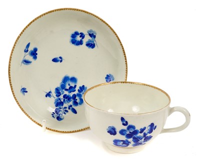 Lot 63 - Worcester dry blue enamel cup and saucer, circa 1770, decorated with floral sprays, with gilt dentil border, the saucer 12.75cm diameter