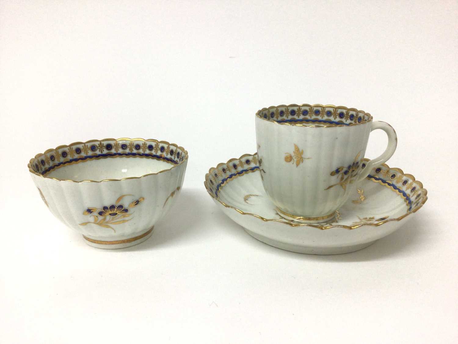 Lot 66 - Caughley trio, circa 1790, of fluted form, decorated in underglaze blue and gilt with floral sprays, 'S' marks, the saucer 13.5cm diameter