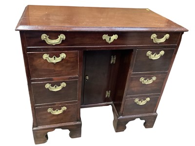 Lot 1218 - Georgian mahogany kneehole desk with seven drawers, brass handles and central cupboard below on bracket feet, 84cm wide, 44cm deep, 75.5cm high